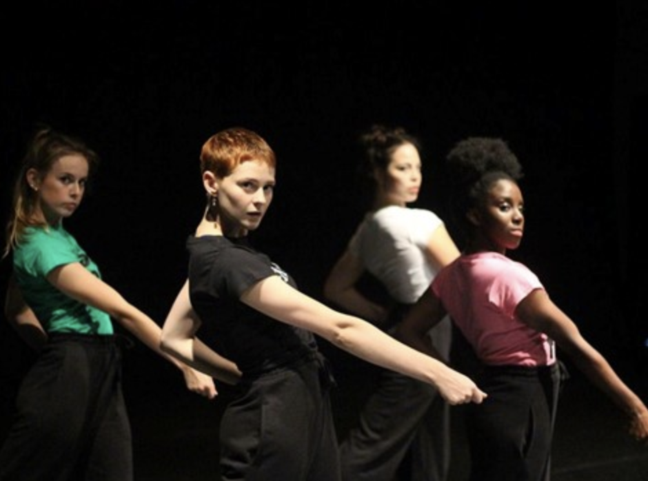 Four women contemporary dancers in staggered line all pointing with right arm diagonally to the ground whilst looking to camera and leaning back.