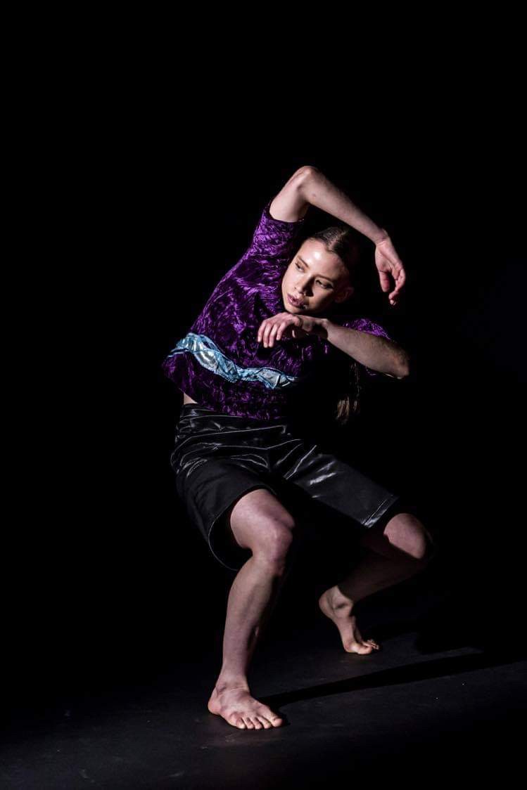 Image of Felicity Bray dancer moving her arm over her head against a black backdrop